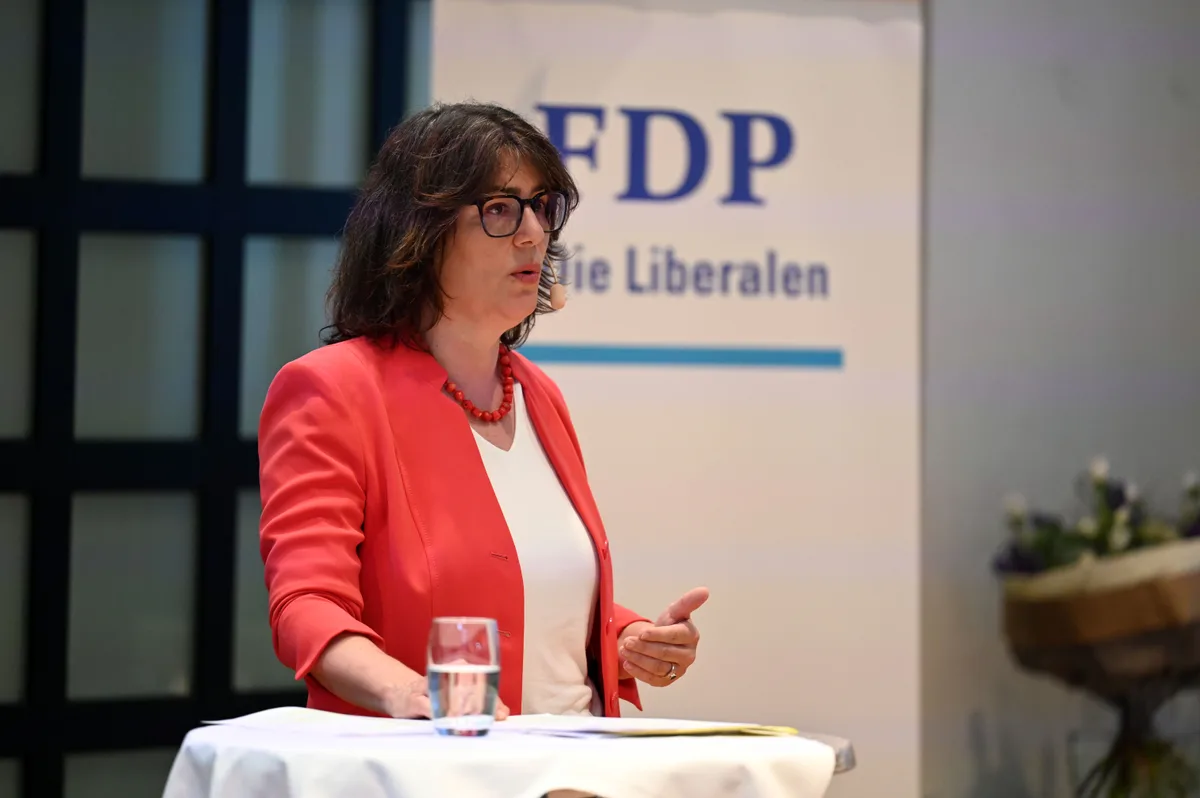 Der Auftritt von Monika Keller wirkt lebendig und authentisch. Monika Keller steht an einem Tischchen, redet und gestikuliert.